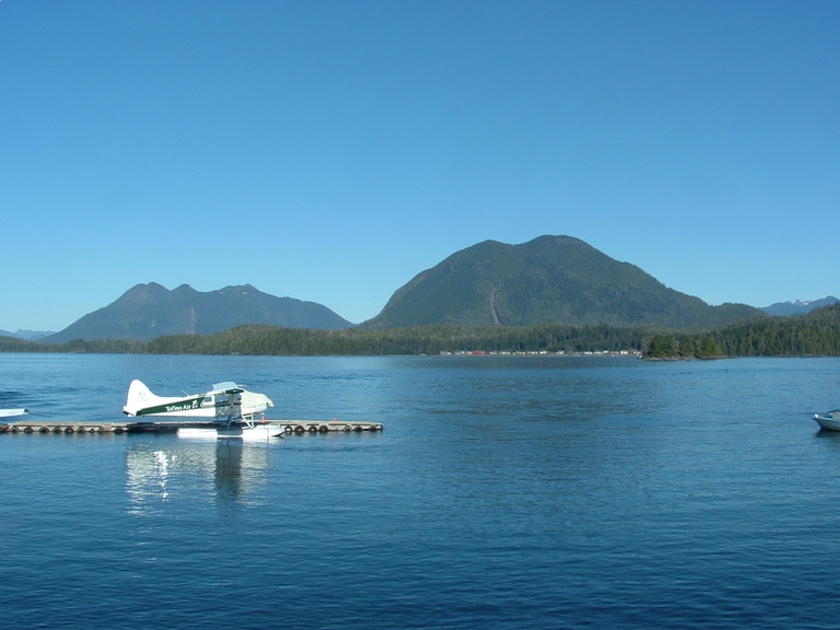 Plane on the water, in front of a mountain.