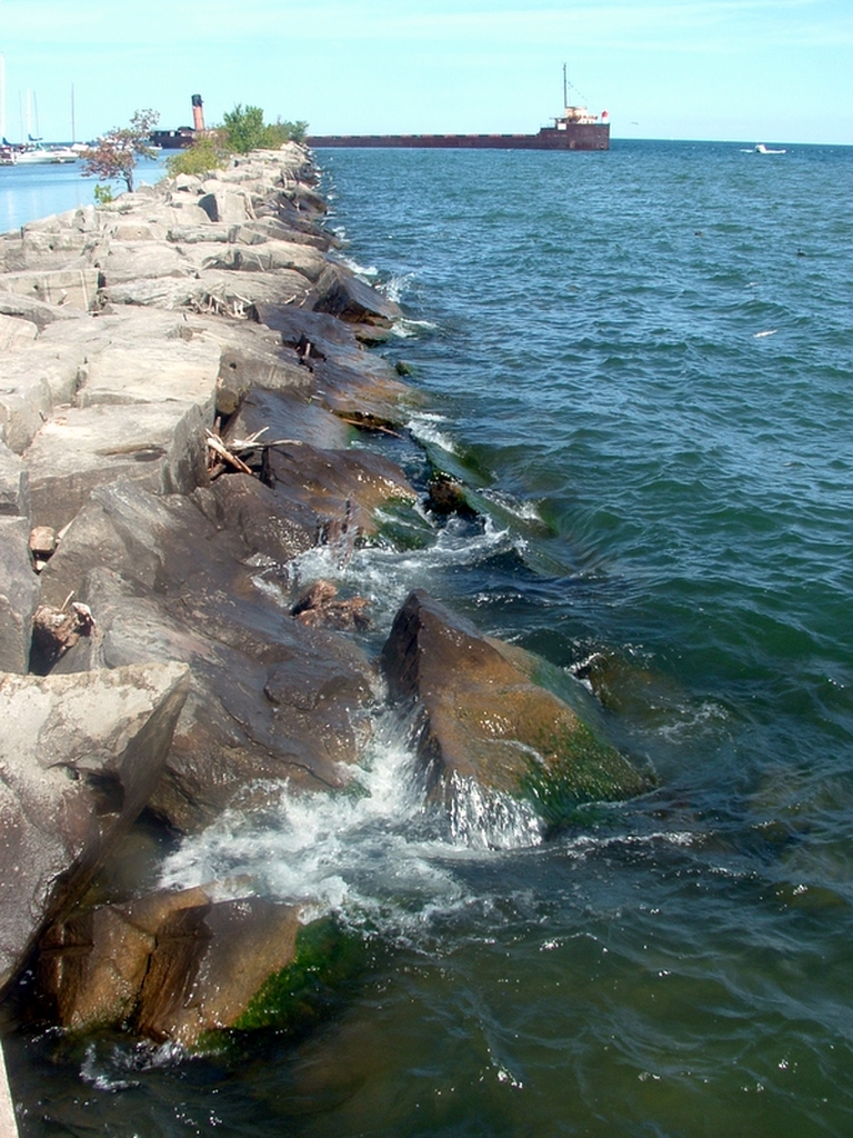 A rock pier with an abandoned ship at the end