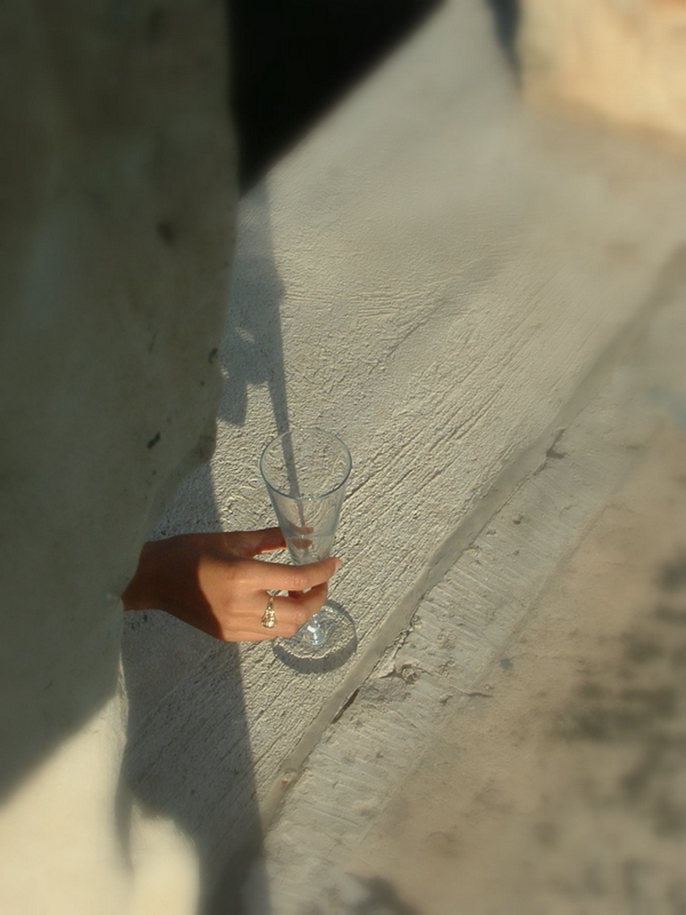 A hand through an archway, holding a glass.